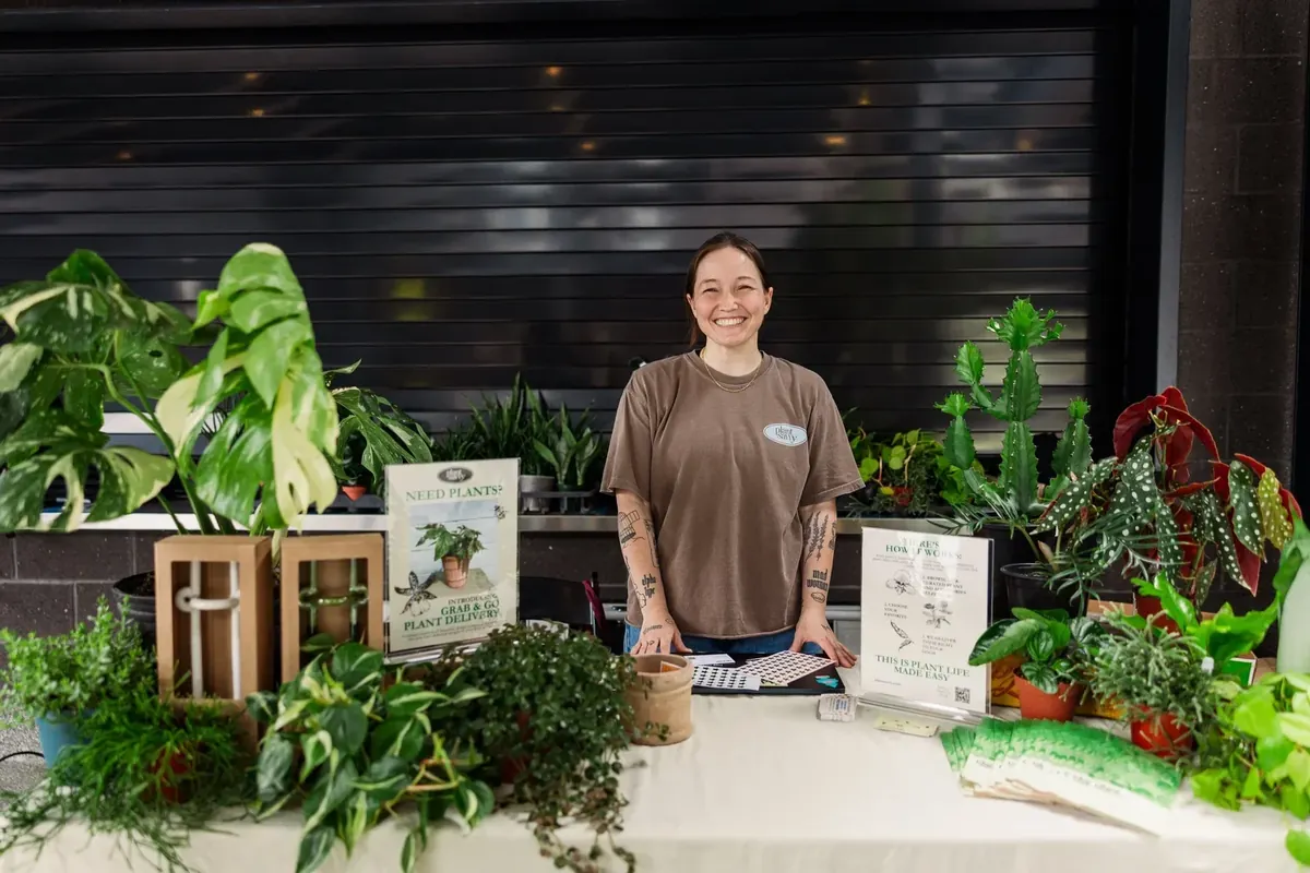 Jordan Woodcock, Operations Coordinator at Plant Savvy, standing behind a table of plants